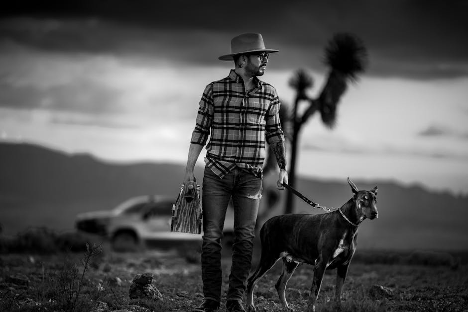 Black and white photo of man with hat and dog in Guanajuato's dramatic landscape.